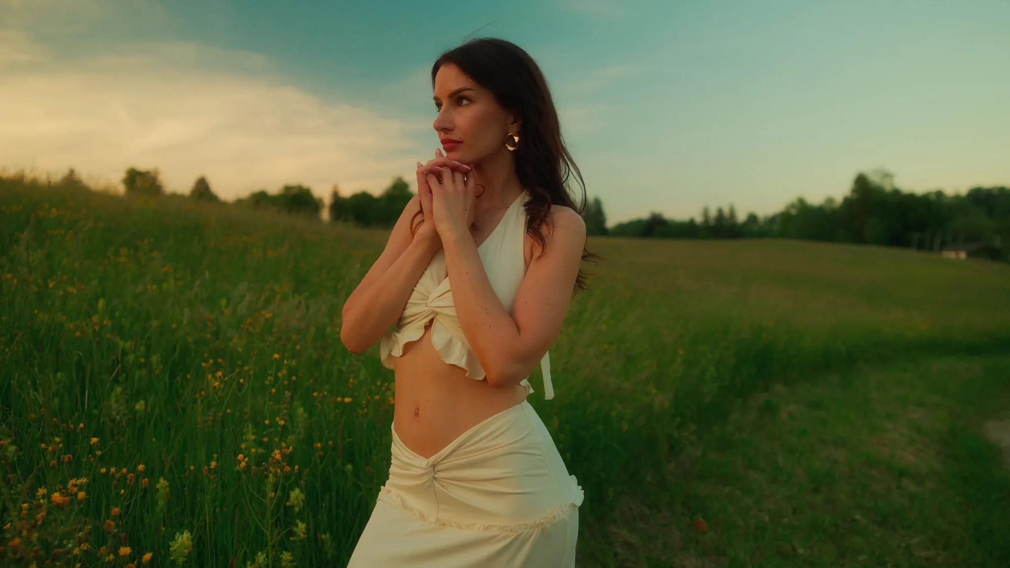 A meadow at golden hour graded with Helios Grade: warm light on skin, a deep teal sky and rich greens.